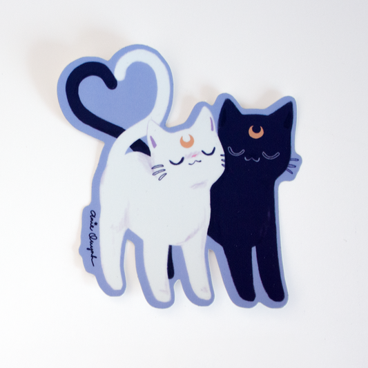 Black and white sailor moon cats with their tails shaped as a heart. 